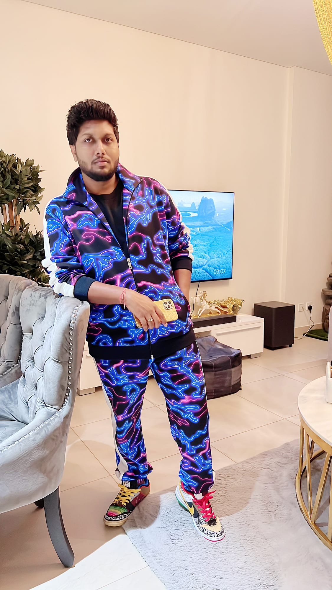 Vinay Anuragh in a neon-patterned track suit leaning on a velvet armchair
